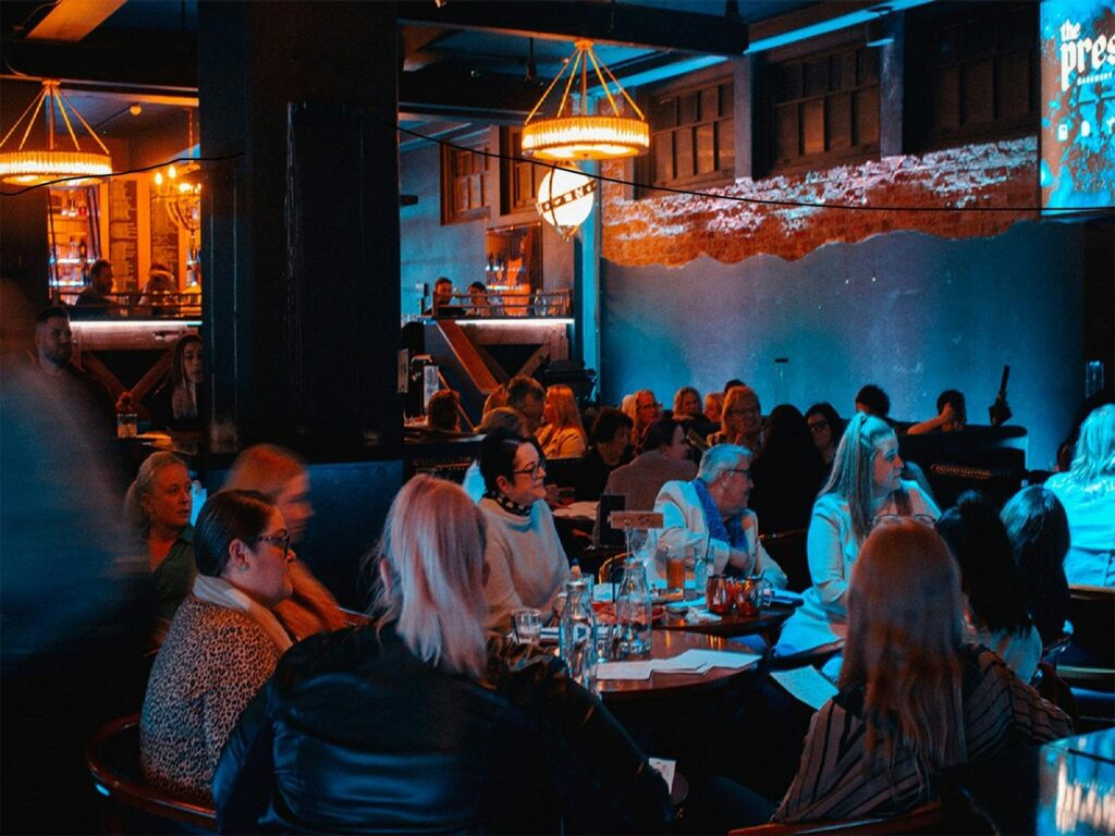 Attentive crowdgathered around tables enjoying dining and the entertainment on offer for the evening